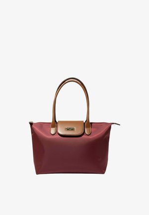 Sac cabas marron avec poignées en cuir marron et rabat, plaque de marque dorée et fermeture éclair sur le dessus sur fond blanc.