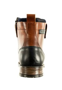Botte en cuir marron avec un capuchon de orteil en cuir noir, talon en bois et col en tissu. Elle dispose d'une boucle en cuir à l'arrière et d'une fermeture éclair sur le côté.