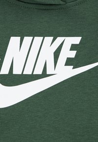 Sudadera verde con un gran logo y swoosh en blanco de "NIKE", hecha de una tela suave y texturizada.