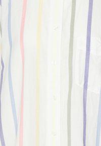 Chemise à boutons en tissu léger, présentant des rayures verticales roses, jaunes, vertes et lavande sur fond blanc, avec une poche sur la poitrine.