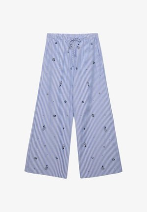 Niebiesko-białe pionowo prążkowane spodnie o szerokich nogawkach z małymi czarno-białymi wzorami kwiatowymi i sznurkiem w pasie.