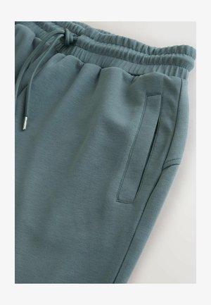 Cotton blend sweatpants in muted teal. Features an elastic waistband with drawstrings and a side pocket. Soft, smooth texture.