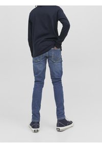 Mörk långärmad skjorta tillsammans med ljusblå slim-fit jeans. Jeans har bakfickor och subtila sömdetaljer. Sneakers i mörkblå.
