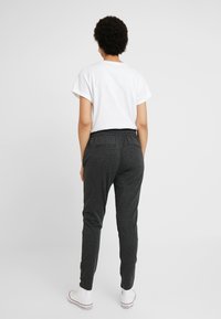 Grå sweatpants med elastisk midjeband, två bakfickor, kombinerade med en vit t-shirt med kort ärm och vita sneakers.