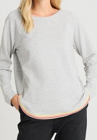 Top gris de manga larga con escote redondo y dobladillo de rayas multicolores. Tejido suave con un ajuste relajado y mangas raglán.