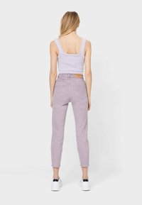 Levandulové džíny s vysokým pasem a zúženými nohavicemi, s zadními kapsami, kombinované s načechraným svetříkem světle fialové barvy a bílými teniskami.