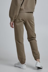 Khaki spalvos džinsai su elastinėmis rankovėmis, pagaminti iš minkštos medvilnės mišinio medžiagos. Sujungti su baltais sportbačiais, pasižyminčiais paprastu ir elegantišku dizainu.