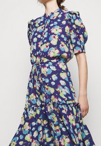 Květinové šaty s námořnickým základem, zdobené živými multikolorovými květy, s nabíranými rukávy, zapínáním na knoflíky vpředu a detaily ve formě nabraného pasu.