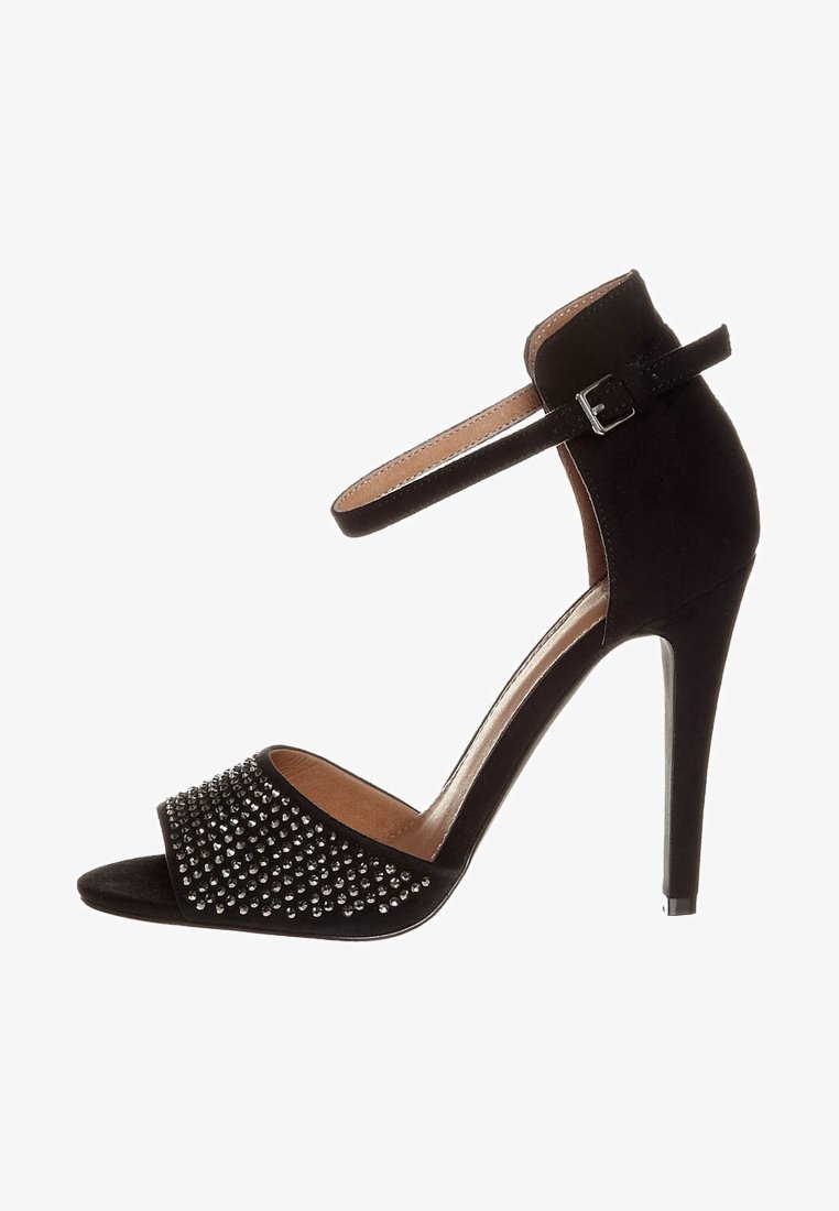 Sandale à talon haut noire avec un dessus en suede, bout ouvert, bride de cheville avec boucle et un design décoratif clouté à l'avant.