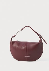Burgundy läderhandväska med rundad form, dragkedjestängning och justerbar rem. Har en logotagg på framsidan.