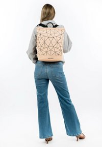 Mochila de color melocotón con un patrón geométrico negro, correas ajustables negras y forma rectangular. El nombre de la marca "SURI FREY" es visible en la parte inferior.