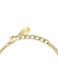 Gouden kettingarmband met in elkaar grijpende schakels, voorzien van een sluiting met een kreeftsklip en een rechthoekig label gegraveerd met "Karl." Gladde, glanzende afwerking.
