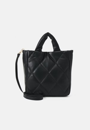 Sac à main noir en similicuir matelassé avec deux poignées courtes rembourrées et une bandoulière longue détachable sur un fond uni.