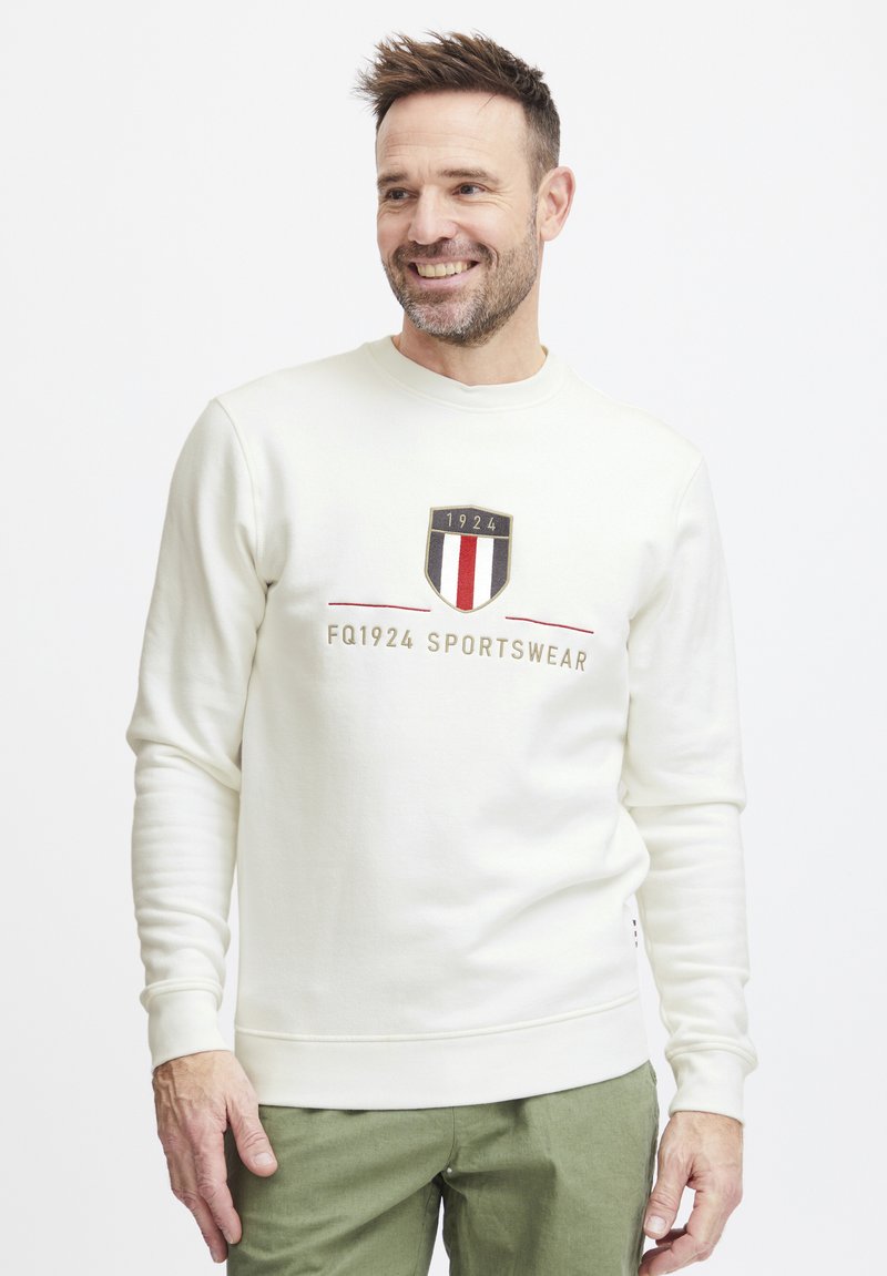 Hvit sweatshirt med rund hals, med et trykt merke som har "1924" og striper i rødt og blått. Myk tekstur, ribbede mansjetter og nedre kant.