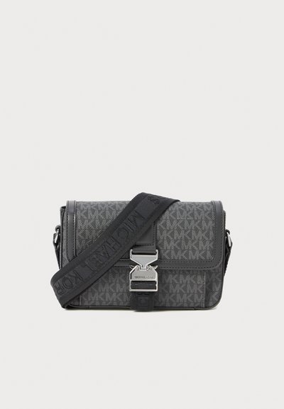 Sac bandoulière gris à motif, fabriqué en matériau texturé, doté d'un fermoir en métal et d'une bandoulière ajustable avec des accents noirs.