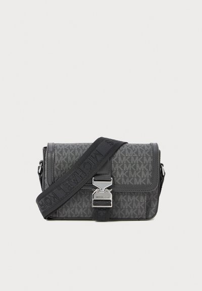 Sac bandoulière gris à motif, fabriqué en matériau texturé, doté d'un fermoir en métal et d'une bandoulière ajustable avec des accents noirs.