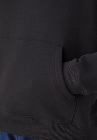 Black sweatshirt with a kangaroo pocket. Made of soft, textured fabric, featuring ribbed cuffs and hem, showcasing a simple, classic design.