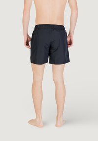 Pantaloni da bagno neri con cintura elastica, texture liscia e lunghezza sopra il ginocchio. Nessun motivo o stampa visibile.