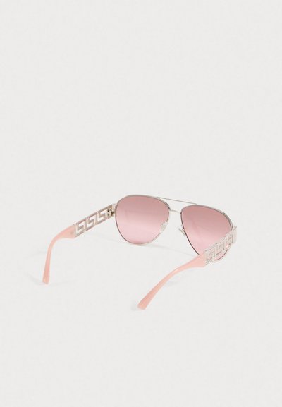 Ochelari de soare aviator cu lentile roz, ramă din metal argintiu și brațe roz cu un design geometric decupat.