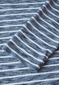 Textil i blått och vitt rutmönster. Har växlande horisontella ränder med olika bredder, slät yta och elastiskt tyg.