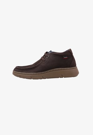 Zapatos de cuero marrón con un perfil bajo, que cuentan con una punta redonda, detalles de costura y una suela de goma beige flexible. Cierre con cordones.