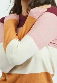 Pull à manches longues avec rayures horizontales de couleur bordeaux, rose, crème et moutarde ; fabriqué en tissu doux avec des poignets côtelés.