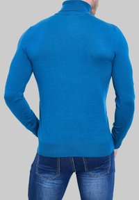 Pull en maille ajusté bleu avec un col haut, des manches longues, des poignets et un ourlet à côtes. La vue arrière montre une texture lisse et une forme contour.