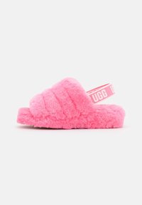 Różowe, puszyste klapki UGG z pikowanym wierzchem i elastycznym paskiem na pięcie z logo na białym tle.