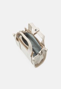 Sac à main en cuir beige avec une surface texturée, deux poignées et une fermeture éclair. L'intérieur est bleu clair avec un compartiment spacieux.