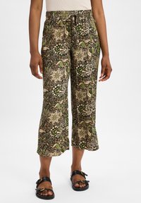 Pantalons palazzo en tissu à motif, ornés de designs floraux et de feuilles dans des tons de vert, beige et noir ; taille élastique et longueur cropped.