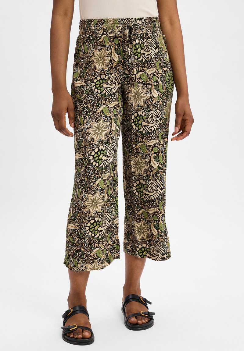 Pantalons palazzo en tissu à motif, ornés de designs floraux et de feuilles dans des tons de vert, beige et noir ; taille élastique et longueur cropped.