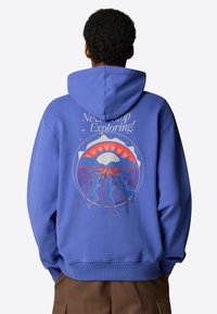 Blue hoodie with a graphic on the back featuring a sunset, mountains, and silhouettes of people running, with "Never Stop Exploring!" text above.