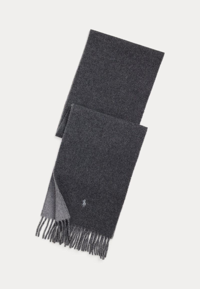 Bufanda de lana de color gris oscuro doblada con extremos con flecos y un pequeño logo bordado cerca de un borde sobre un fondo claro.