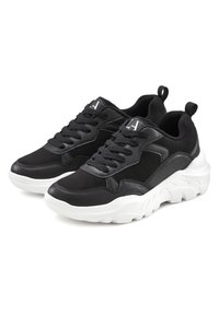 Scarpe da atletica nere realizzate in pelle sintetica e scamosciata. Presentano un design con lacci, colletto imbottito e suola bianca spessa con dettagli testurizzati.