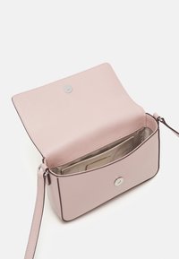 Borsa crossbody in pelle rosa chiaro con una superficie liscia, chiusura a pressione in argento e una tasca interna per carte. Forma rettangolare compatta.