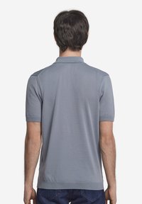 Grå polo-shirt med korta ärmar, en ribbad krage och rak fåll. Slätt tyg utan mönster eller synlig hårdvara.