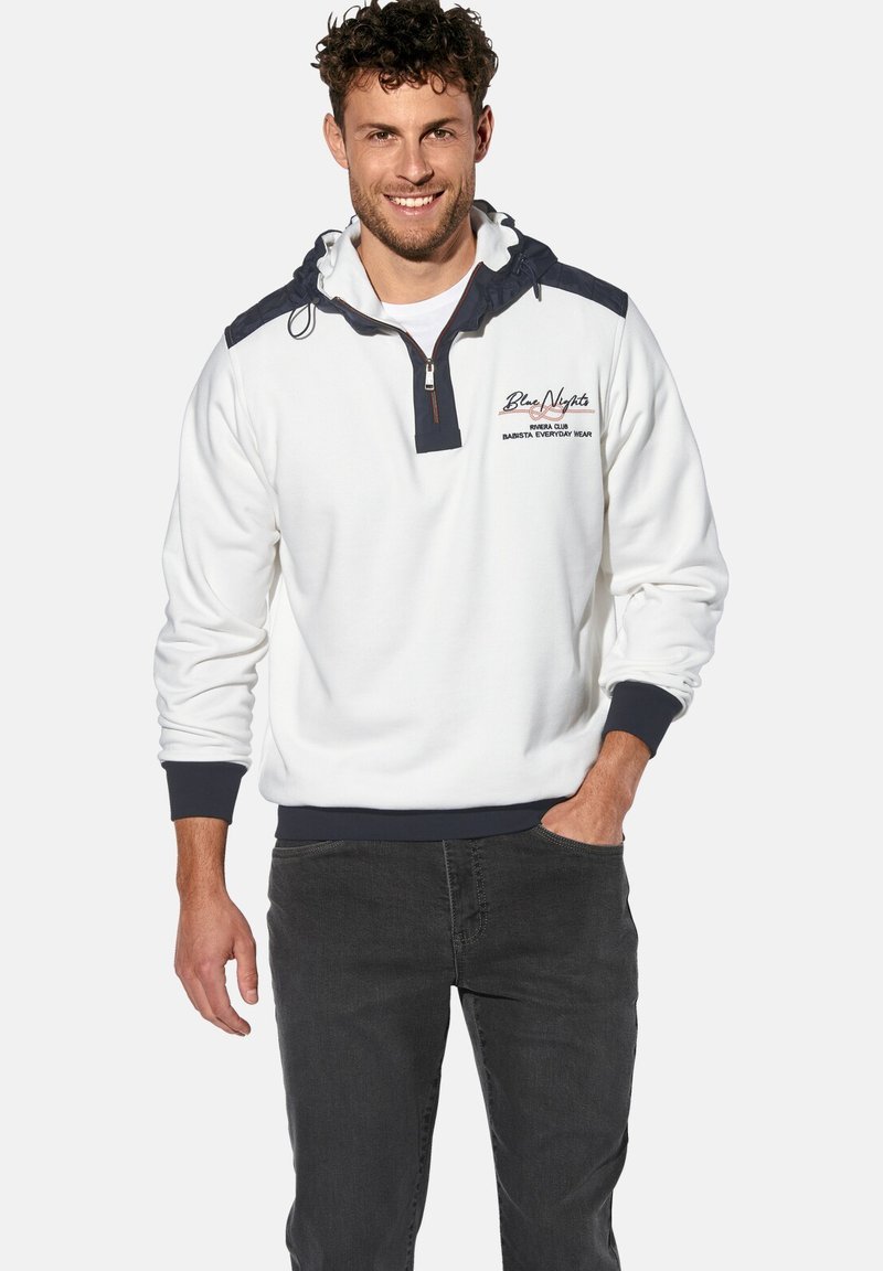 Weißer Pullover mit navyblauen Akzenten, halbem Reißverschlusskragen, Kapuze und gerippten Bündchen. Verfügt über gestickten Text auf der Brust. Weicher Stoff.