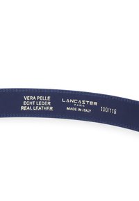Interno di una cintura in pelle blu scuro che mostra testo impressa: "Vera Pelle Echt Leder Real Leather," "Lancaster Paris," "Fatto in Italia," e taglia "100/115."