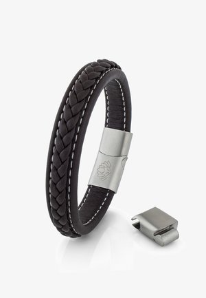 Črn pleten usnjen zapestnica s srebrnim kovinskim sponko. Ima kontrastno belo šivanje in brušen znamenje leva na sponki.
