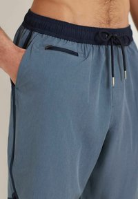Vaaleansiniset shortsit, jotka on valmistettu sileästä ja kevyestä kankaasta. Varustettu joustavalla vyötäröllä, jossa on nyöri sekä vetoketjullinen tasku.