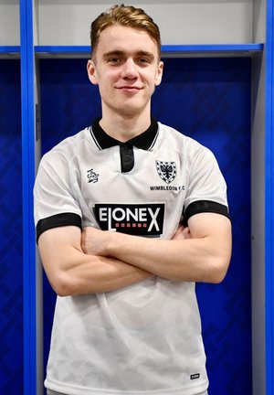 Witte voetbalshirt met zwarte kraag en manchetten, voorzien van een geometrisch patroon, clublogo en een groot sponsorlogo in het midden.