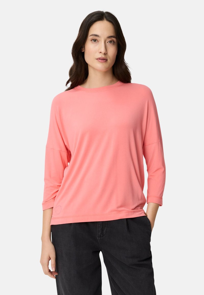 Koralfarvet oversize skjorte med rund hals og trekvartærmer, lavet af et blødt, let stof. Enkelt design med få detaljer.