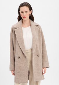Cappotto in lana beige con un design strutturato, colli oversize e due bottoni scuri, caratterizzato da una texture morbida e una vestibilità rilassata.
