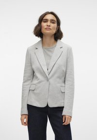 Světle šedý blazer z měkké tkaniny, s klopovým límcem, zapínáním na jeden knoflík a dvěma předními náprsními kapsami.