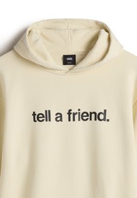 Cream-colored hoodie with a front graphic in bold black text reading "tell a friend." Features a drawstring hood and soft texture.