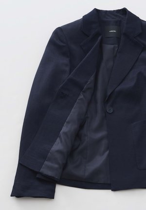 Marineblauwe blazer van textuurstof met een enkele knoopsluiting en gekante lappen. De gevoerde binnenkant heeft bijpassende blauwe stof.