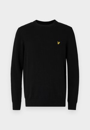 Sort crew neck sweater lavet af blødt materiale. Har lange ærmer og et lille gult logo på venstre bryst. Sørger for en tætsiddende pasform ved taljen.