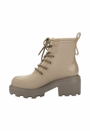 Beiger glänzender Knöchelstiefel mit klobigem Absatz, dicker Profilsohle, Schnürung vorne und Zuglaschen am Fersenkragen für einfaches Anziehen.