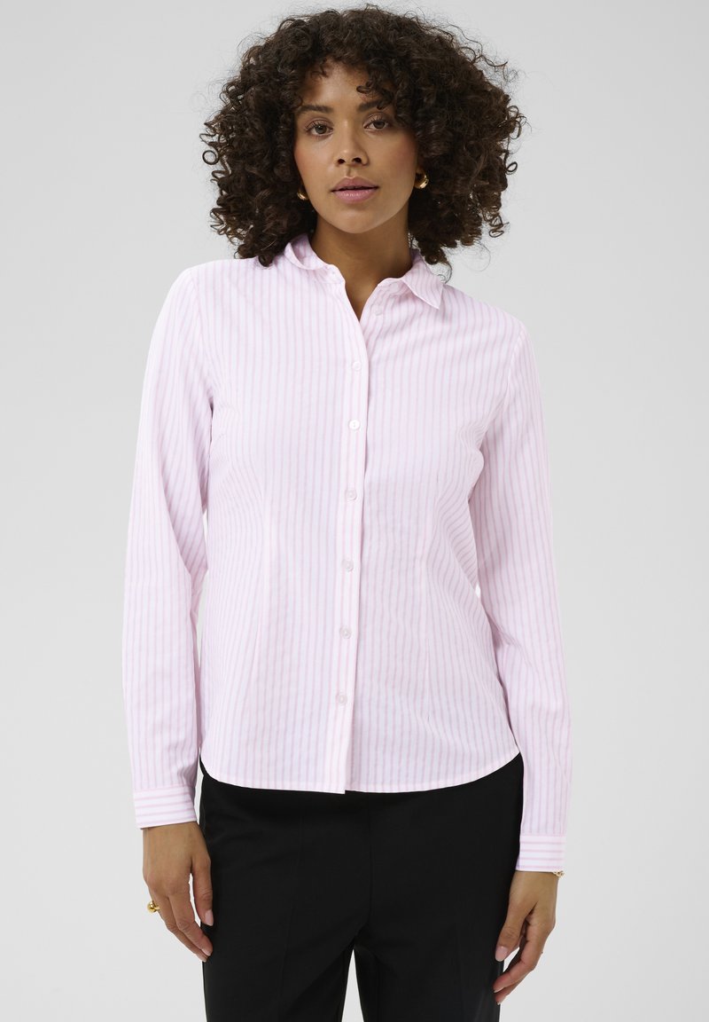 Chemise rose pâle à rayures avec boutons, manches longues, col à revers et ourlet droit. Le tissu est lisse, avec de fines lignes verticales.