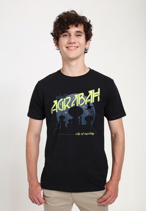 Sort bomulds t-shirt med et farverigt grafisk silhuet af en bylinje, med teksten "besøg AGRABAH" og "mysternes by" nedenfor.